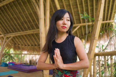 tropikal orman manzaralı güzel ahşap joglo stüdyoda yoga ve meditasyon egzersiz açık havada pratik genç doğal ve çekici Asyalı Çinli kadın