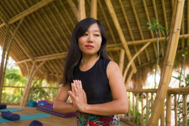 tropikal orman manzaralı güzel ahşap joglo stüdyoda yoga ve meditasyon egzersiz açık havada pratik genç doğal ve çekici Asyalı Çinli kadın