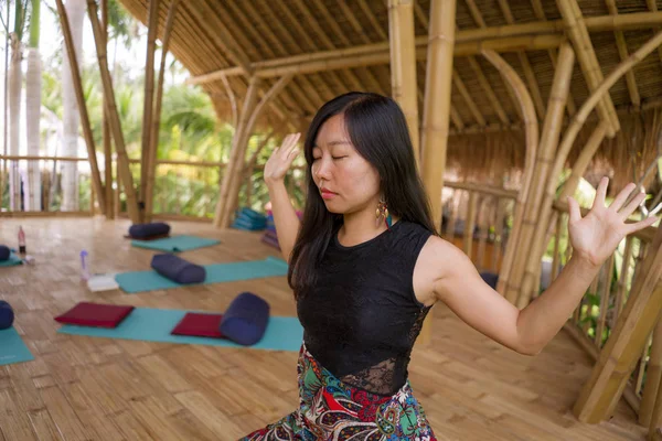 Jeune femme chinoise asiatique naturelle et attrayante pratiquant le yoga et l'exercice de méditation à l'extérieur dans un magnifique studio de joglo en bois avec vue sur la jungle tropicale — Photo