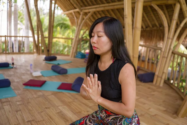 Joven mujer china asiática natural y atractiva practicando yoga y ejercicio de meditación al aire libre en un hermoso estudio de joglo de madera con vista a la selva tropical — Foto de Stock