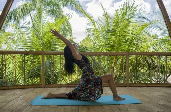 Joven mujer china asiática natural y atractiva practicando yoga y ejercicio de meditación al aire libre en un hermoso estudio de joglo de madera con vista a la selva tropical — Foto de Stock