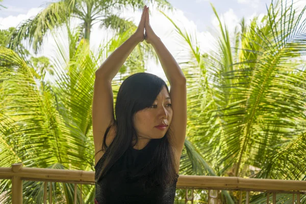 Jeune femme chinoise asiatique naturelle et attrayante pratiquant le yoga et l'exercice de méditation à l'extérieur dans un magnifique studio de joglo en bois avec vue sur la jungle tropicale — Photo