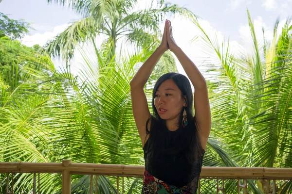 Joven mujer china asiática natural y atractiva practicando yoga y ejercicio de meditación al aire libre en un hermoso estudio de joglo de madera con vista a la selva tropical — Foto de Stock