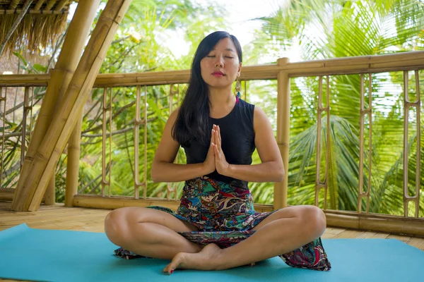 Joven mujer china asiática natural y atractiva practicando yoga y ejercicio de meditación al aire libre en un hermoso estudio de joglo de madera con vista a la selva tropical — Foto de Stock