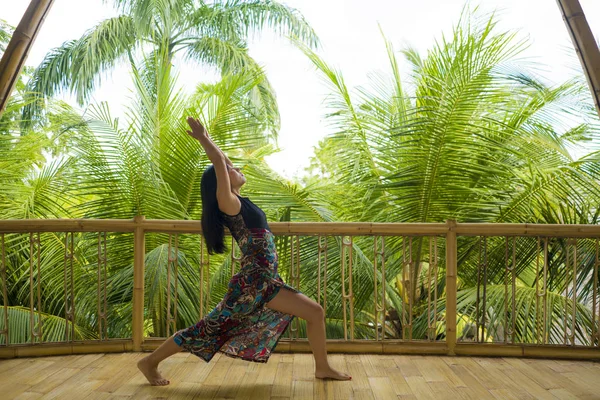 Giovane donna cinese asiatica naturale e attraente che pratica yoga e meditazione esercizio all'aperto in bellissimo studio joglo in legno con vista sulla giungla tropicale — Foto Stock