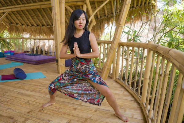 Jeune femme chinoise asiatique naturelle et attrayante pratiquant le yoga et l'exercice de méditation à l'extérieur dans un magnifique studio de joglo en bois avec vue sur la jungle tropicale — Photo