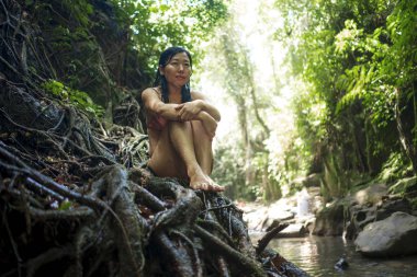 tropik büyülü ormanda güzel kadın . Gizemli ve büyülü bir duygu ile tropikal cennet ormanda ağaç gövdesi üzerinde oturan bikini Genç çekici Asyalı Koreli kız