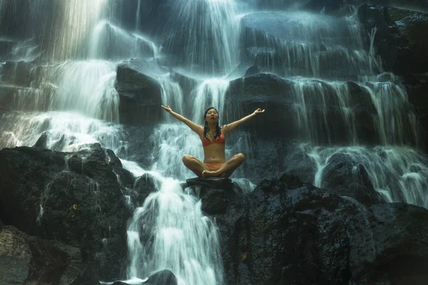 natural portrait of young beautiful and happy Asian Korean woman in bikini enjoying nature at tropical paradise waterfall with magical feeling in soul inspiration