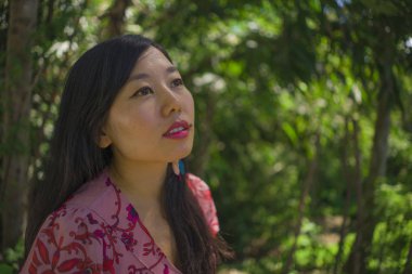 açık havada zarif elbiseli genç güzel ve mutlu Asyalı Çinli kadının yaz yaşam tarzı portresi yeşil şehir parkı veya ahşap sakin ve neşeli yürüyüş