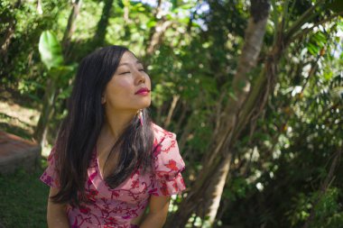 açık havada zarif elbiseli genç güzel ve mutlu Asyalı Koreli kadının yaz yaşam tarzı portresi yeşil şehir parkı veya ahşap sakin ve neşeli yürüyüş