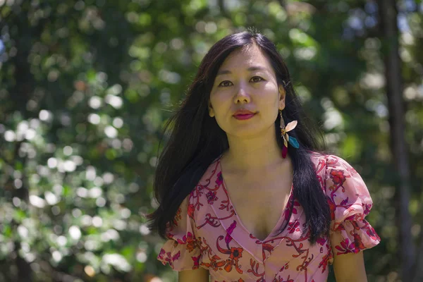 Летний образ жизни портрет молодой красивой и счастливой азиатской кореянки в элегантном платье ходить спокойно и весело в зеленом городском парке или лесу — стоковое фото