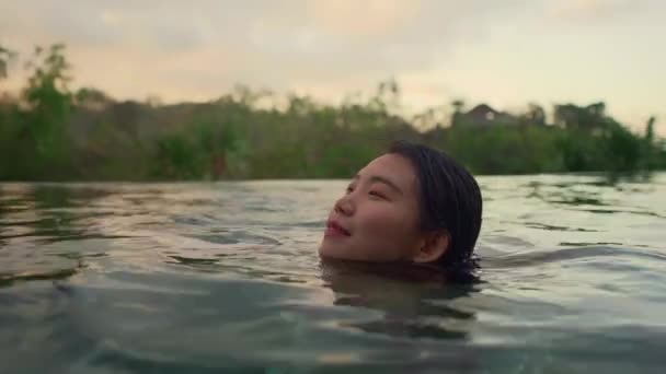户外假期生活方式拍摄年轻美丽和轻松的亚洲中国妇女享受在热带度假胜地游泳池 在夏季日落欣赏热带景观和棕榈树 — 图库视频影像