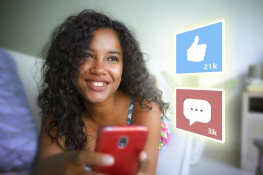 internet sosyal medya uygulaması seviyor ve sohbet yorum simgeleri genç güzel ve mutlu karışık etnik siyah Afro-Amerikan kadın evde cep telefonu kullanarak kompozit