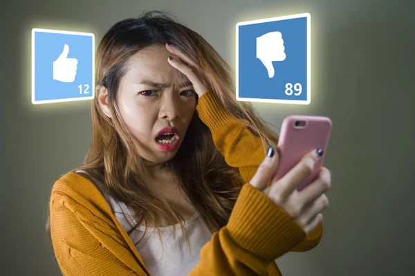 Ung söt och ledsen asiatisk kinesisk flicka känsla olycklig och desperat innehav mobiltelefon ser mer ogillar än gillar på hennes Internet sociala medier post i Cyber mobbning Concept — Stockfoto