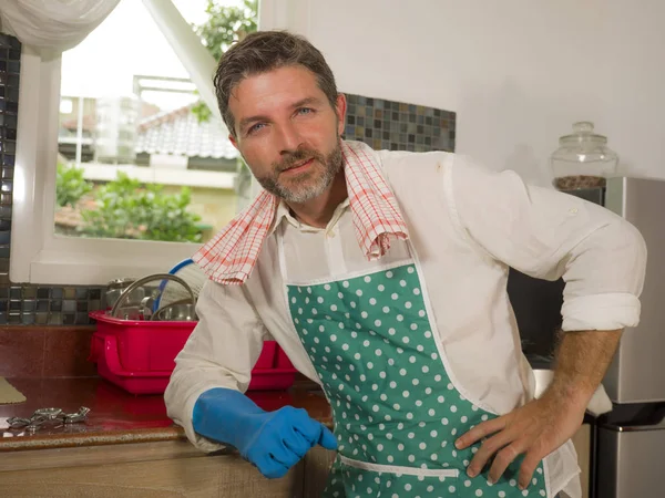 Glücklicher und attraktiver Mann genießt Geschirrspülen zu Hause Küche in Schürze und Putzen Gummihandschuh lächelnd zufrieden Hausaufgaben machen als guter Ehemann — Stockfoto