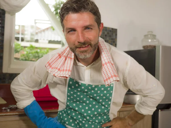 30s a 40s feliz y atractivo hombre usando delantal de cocina posando fresco disfrutando de lavar platos y haciendo tareas domésticas sonriendo satisfecho en casa — Foto de Stock