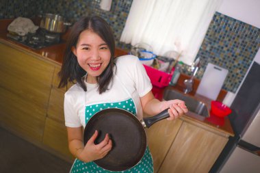mutfak önlük genç güzel ve mutlu Asyalı Çinli kadın pişirme tavası ile hava gitar oynarken ev işleri dans ve evde şarkı zevk zevk