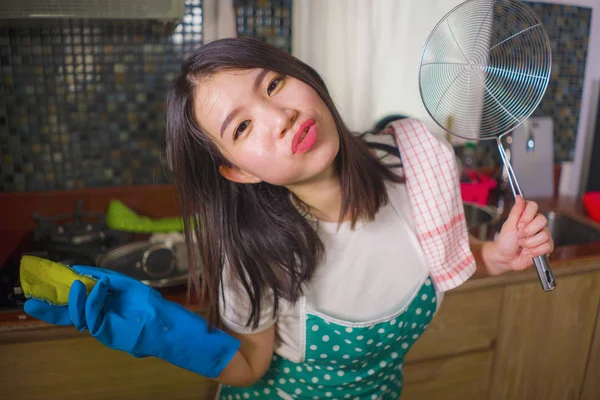 Stile di vita naturale ritratto di giovane bella e felice donna asiatica coreana in cucina grembiule tenuta spugna sorridente allegro godendo faccende domestiche e pulizia — Foto Stock