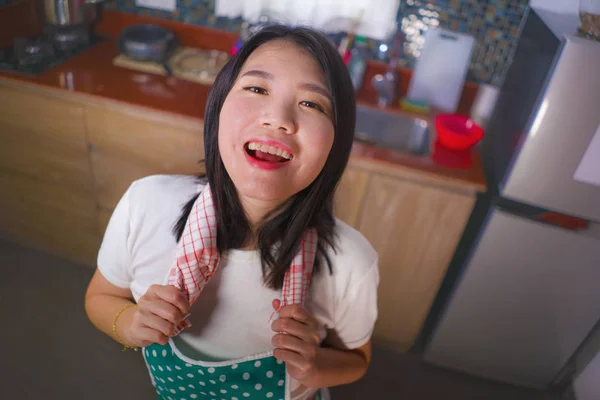 Stile di vita naturale ritratto di giovane bella e felice donna asiatica cinese in cucina grembiule tenendo stoffa piatto sorridente allegro godendo faccende domestiche e pulizia — Foto Stock