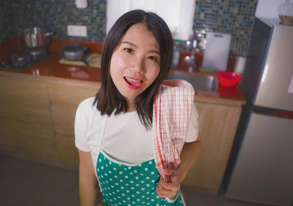 Естественный образ жизни портрет молодой красивой и счастливой азиатской кореянки в кухонном фартуке, держащей блюдо ткань, улыбаясь весело наслаждаясь домашней работой и домашним хозяйством — стоковое фото
