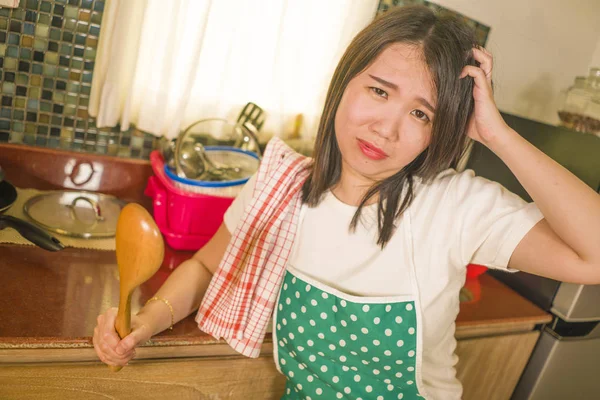 Jeune femme chinoise asiatique fatiguée et stressée dans un tablier de cuisinier s'appuyant sur un évier de cuisine paresseux dans un ménage au visage humide et bouleversé à la maison et pleurant — Photo