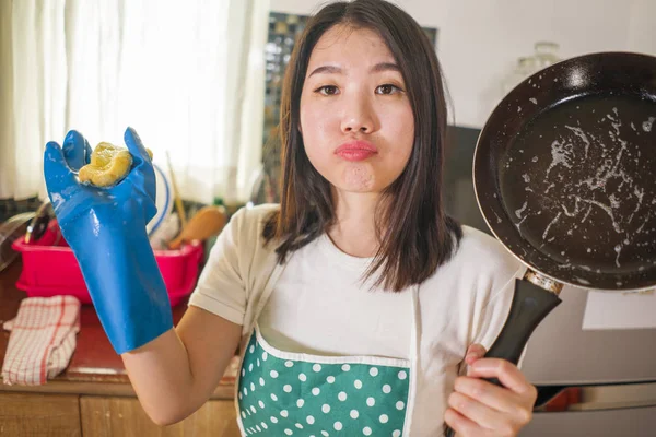 Corvées domestiques style de vie portrait de jeune femme asiatique fatiguée et stressée coréenne dans tablier de cuisinier laver la vaisselle à l'évier de cuisine travaillant paresseux dans le visage lunatique et contrarié faire des travaux ménagers — Photo