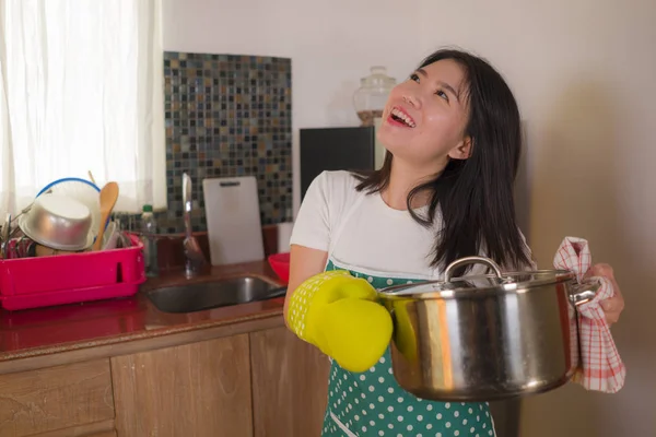 Asiatico casa cuoco ragazza stile di vita ritratto. Giovane donna coreana felice e bella in cucina grembiule e guanto tenendo pentola eccitata e soddisfatta preparare la zuppa — Foto Stock