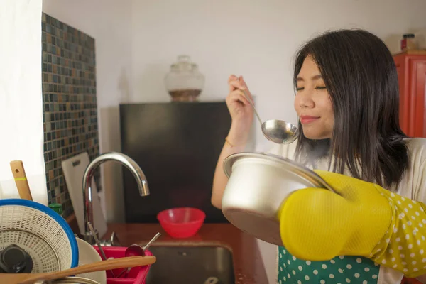 Портрет азиатской кухарки. Молодая счастливая и красивая корейская женщина в кухонном фартуке и перчатке проведение приготовления пищи горшок взволнован и удовлетворен приготовления супа восторженный — стоковое фото