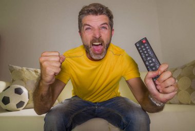 genç mutlu ve heyecanlı adam Tv'de Avrupa futbol maçı izlerken kanepede gol kutluyor futbol fan zafer zevk gibi spastik gesturing deli neşeli çığlık