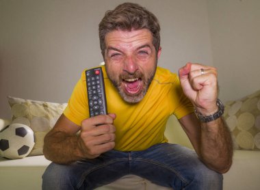 genç mutlu ve heyecanlı adam Tv'de Avrupa futbol maçı izlerken kanepede gol kutluyor futbol fan zafer zevk gibi spastik gesturing deli neşeli çığlık