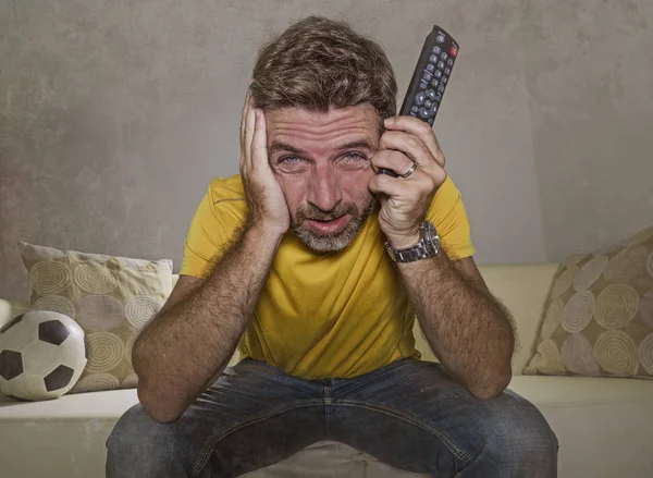 Uomo stressato e nervoso a guardare la partita di calcio in TV seduto a casa divano soggiorno eccitato e con espressione di folle intensa emozione — Foto Stock