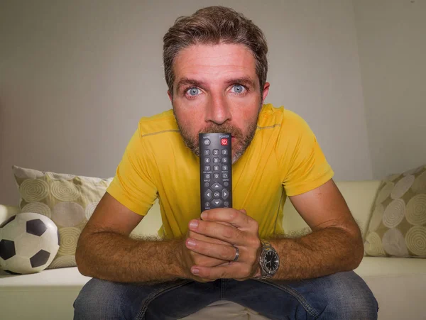 Hombre estresado viendo el partido de fútbol en la televisión sentado en casa sala de estar sofá emocionado y con expresión de emoción intensa loca disfrutando del partido de fútbol — Foto de Stock