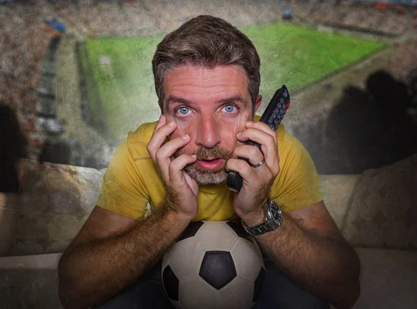 Estádio de futebol composto com homem atraente e estressado assistindo jogo de futebol na TV em casa sofá animado em emoção intensa apreciando o jogo de futebol — Fotografia de Stock