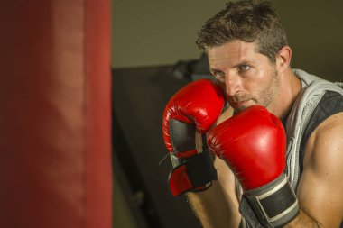 serin ve badass savaşçı bakmak ağır çanta delme fitness kulübünde boks eldiven eğitimi çekici ve şiddetli görünümlü boksör adam 30s 40s spor egzersiz portre