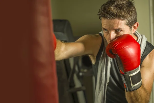 Serin ve badass savaşçı bakmak ağır çanta delme fitness kulübünde boks eldiven eğitimi çekici ve şiddetli görünümlü boksör adam 30s 40s spor egzersiz portre — Stok fotoğraf