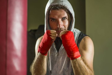 spor fitness yaşam tarzı portre genç mutlu ve terli adam spor salonunda boks ağır çanta üzerinde kapüşonlu yelek eğitim terli dışarı çalışma serin ve badass görünümlü