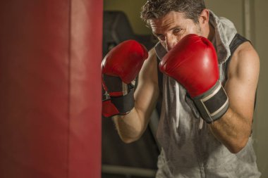 serin ve badass savaşçı bakmak ağır çanta delme fitness kulübünde boks eldiven eğitimi çekici ve şiddetli görünümlü boksör adam 30s 40s spor egzersiz portre