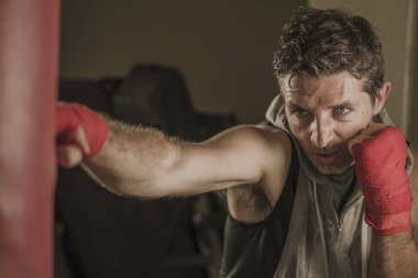 fitness kulübünde genç çekici ve şiddetli görünümlü adam eğitim boks yaşam tarzı spor salonu portre badass savaşçı bakmak bilek sarar ile ağır çanta delme egzersiz yapıyor 