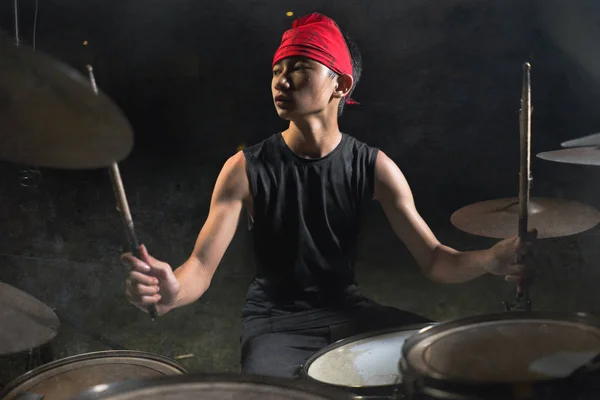 Cool e talentoso asiático americano misto etnia jovem menino tocando bateria na headband praticando e executando música no escuro nevoeiro fase — Fotografia de Stock