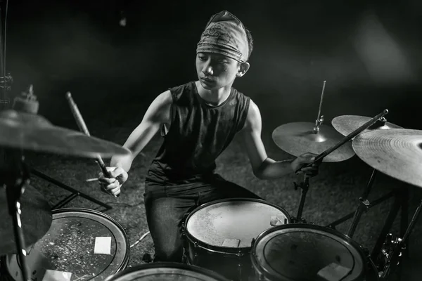 Alter cooler und talentierter asiatisch-amerikanischer gemischter Ethnizität junger Junge, der Schlagzeug im Stirnband spielt, übt und performt Lieder in Dunkelheit und Bühnennebel — Stockfoto