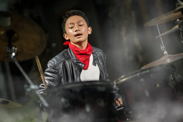 Jovem músico adolescente legal e talentoso tocando bateria em seu 14 anos de idade em jaqueta de couro e estilo banda de bandana rock praticando e executando música no palco — Fotografia de Stock