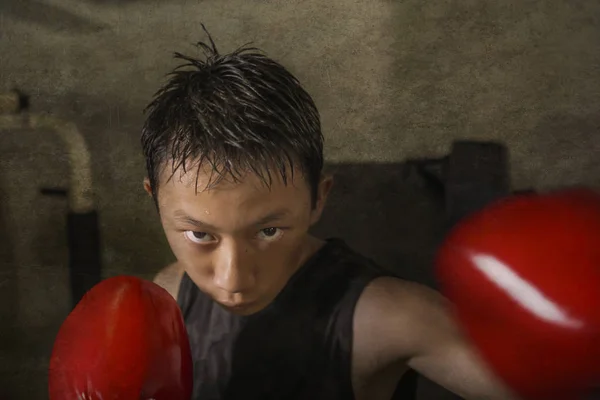 Tough and cool young boy punching on heavy bag . 13 or 14 years old Asian teenager training Thai boxing workout looking defiant as a badass fighter practicing sport — Stock Photo, Image