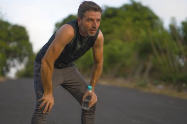 Spor ve spor yaşam tarzı. Genç, çekici, terli ve yorgun bir adamın portresi. Açık havada koşmaktan yorgun düşmüş.