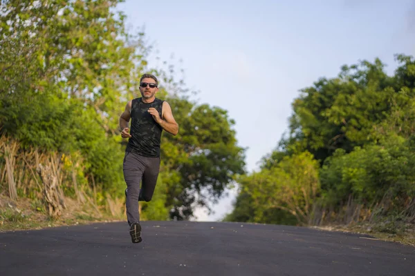 Retrato de estilo de vida de homem jovem atraente e saudável em seus 30 ou 40 anos correndo na estrada do país fazendo jogging treino feliz em belo fundo natural — Fotografia de Stock