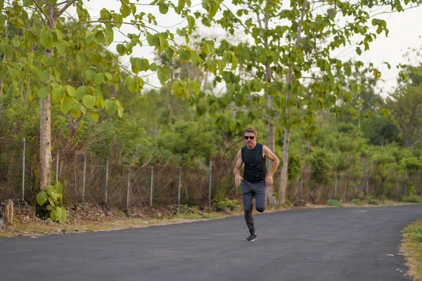 Livsstil porträtt av ung attraktiv och frisk man på 30-talet eller 40-talet kör på land väg gör jogging träning glad på vacker naturlig bakgrund — Stockfoto