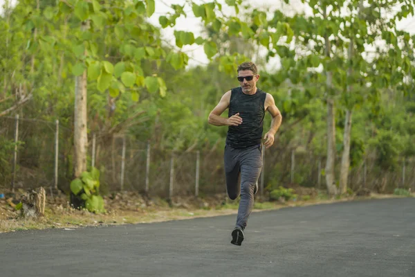 Livsstil porträtt av ung attraktiv och frisk man på 30-talet eller 40-talet kör på land väg gör jogging träning glad på vacker naturlig bakgrund — Stockfoto