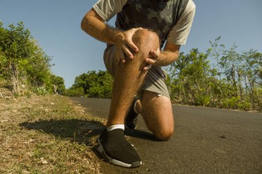 Spor adamının ellerini ve bacaklarını kapatın. Acı çekerken dizine dokunuyor. Fiziksel bir sorun ya da sağlık hizmetleri konseptinde spor yaparken sakatlanıyor.