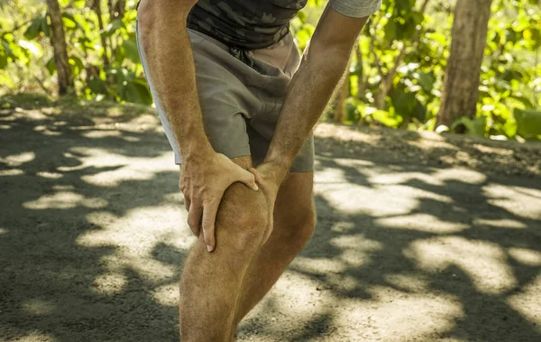 Spor yapan bir adamın spor kazasında ve sağlık konseptinde spor yaparken dizine dokunarak acı çekmesi ya da sakatlanması sonucu ellerini ve bacaklarını kapatın.