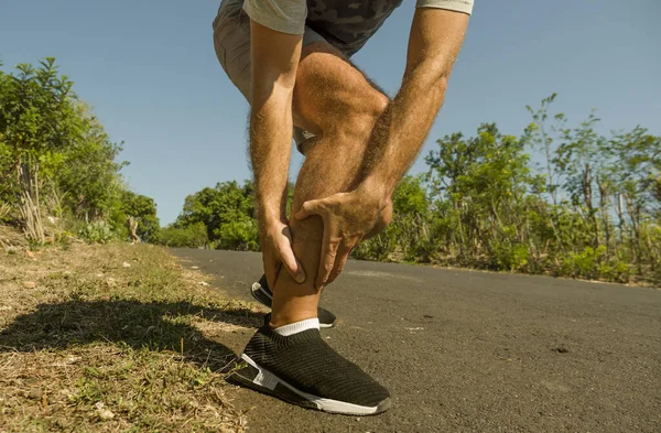 Nahaufnahme Hände und Beine des Sportlers verletzt Berührung seines Knöchels in Schmerzen leiden körperliche Probleme oder eine Verletzung beim Lauftraining im Freien in Gesundheitskonzept — Stockfoto