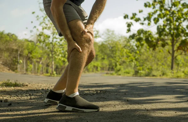 Närbild händer och ben sport man skadad vidröra knät i smärta lider fysiska problem eller någon skada under löpning träning utomhus i sjukvården koncept — Stockfoto